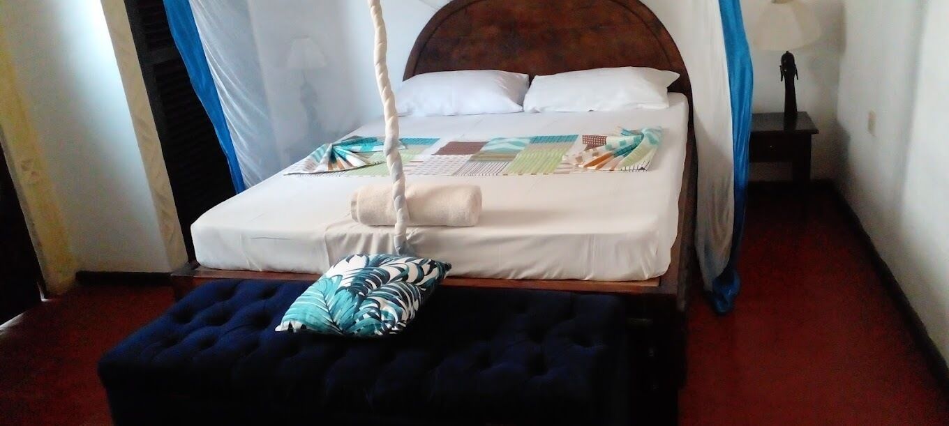 A bed with a canopy, a hanging chair, and a small table with a lamp.