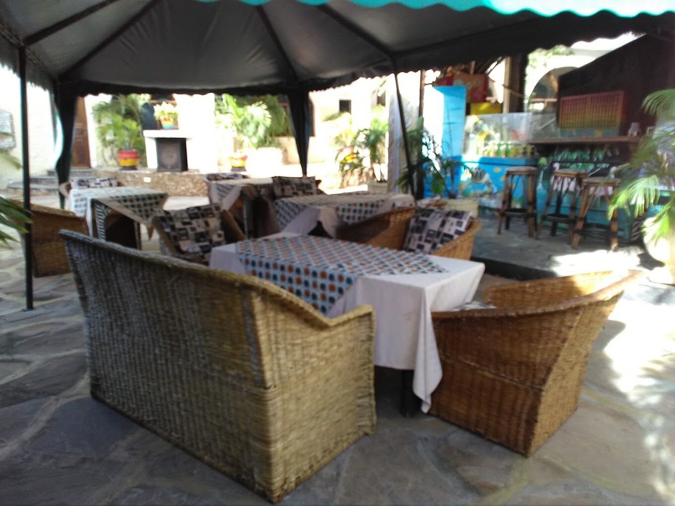 An outdoor seating area with wicker furniture and tables covered with white tablecloths.