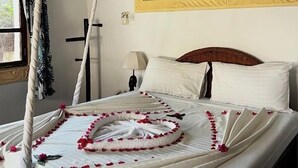 A bed with a canopy, a painting of swans, and a nightstand with a lamp. - Malindi Breeze Point Hotel (Malindi)