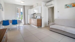 Un appartement moderne comprenant un coin repas, une kitchenette et un salon avec un canapé.