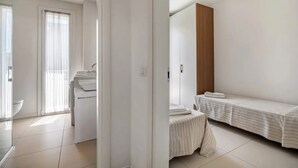 Une chambre moderne et minimaliste, avec un lit, une petite table et une fenêtre avec des rideaux.