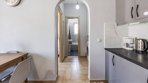 Une cuisine moderne avec une table et des chaises en bois, une machine à café et un lave-linge en arrière-plan.