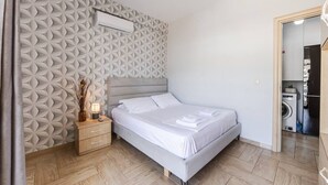 Une chambre à coucher comprenant un lit, une table de chevet, une lampe et un mur orné d’un motif géométrique.