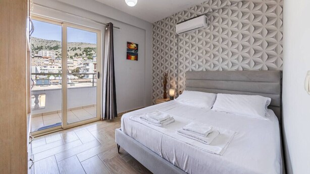 Une chambre d’hôtel avec un lit, une vue sur la ville depuis un balcon et un mur décoré de motifs.