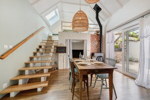 A dining area with a wooden table, chairs, and a staircase leading to an upper level. - Charming Townhouse in St Renan (Saint-Renan)