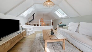 A modern loft apartment with a large TV, wooden furniture, a white sofa, and a skylight. - Charming Townhouse in St Renan (Saint-Renan)