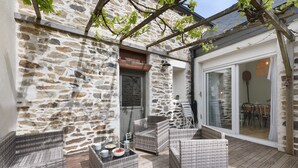 A stone wall, wicker furniture, and a wooden deck. - Charming Townhouse in St Renan (Saint-Renan)