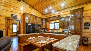 A wooden cabin interior with a kitchen featuring a large island, wooden cabinets, and a stone countertop. - Hoot's Hideaway w/ Hot Tub (Broken Bow)
