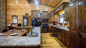 A spacious kitchen with wooden cabinets, granite countertops, and modern appliances. - Hoot's Hideaway w/ Hot Tub (Broken Bow)