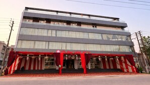 A multi-story hotel with a modern facade, a red awning, and a staircase leading to the entrance. - Hotel The Royal Knot (Kanpur)