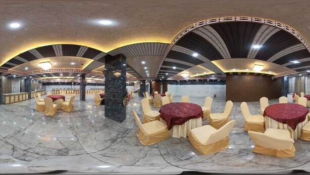 A spacious banquet hall with marble flooring, multiple round tables with chairs, and a high ceiling with decorative arches. - Hotel The Royal Knot (Kanpur)