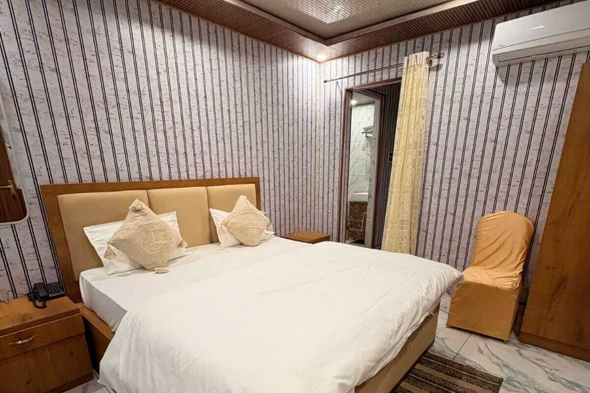 Quarto com uma cama grande, cabeceira de madeira e ventilador de teto.
