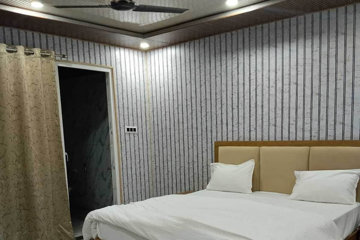 Quarto com cama, cortinas e ventoinha no teto.