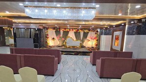 A banquet hall with a stage, red and beige chairs, and a chandelier. - Hotel The Royal Knot (Kanpur)