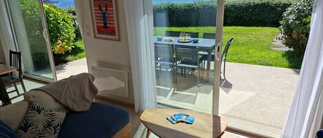 A room with a sofa, a small table, and a view of the sea through a glass door.