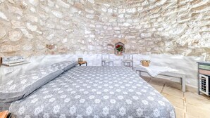 Ein Zimmer mit Stehwänden, einem Bett, einem kleinen Tisch und einer Bank.