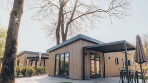 En modern byggnad med stora fönster, en täckt uteplats och en gräsyta.