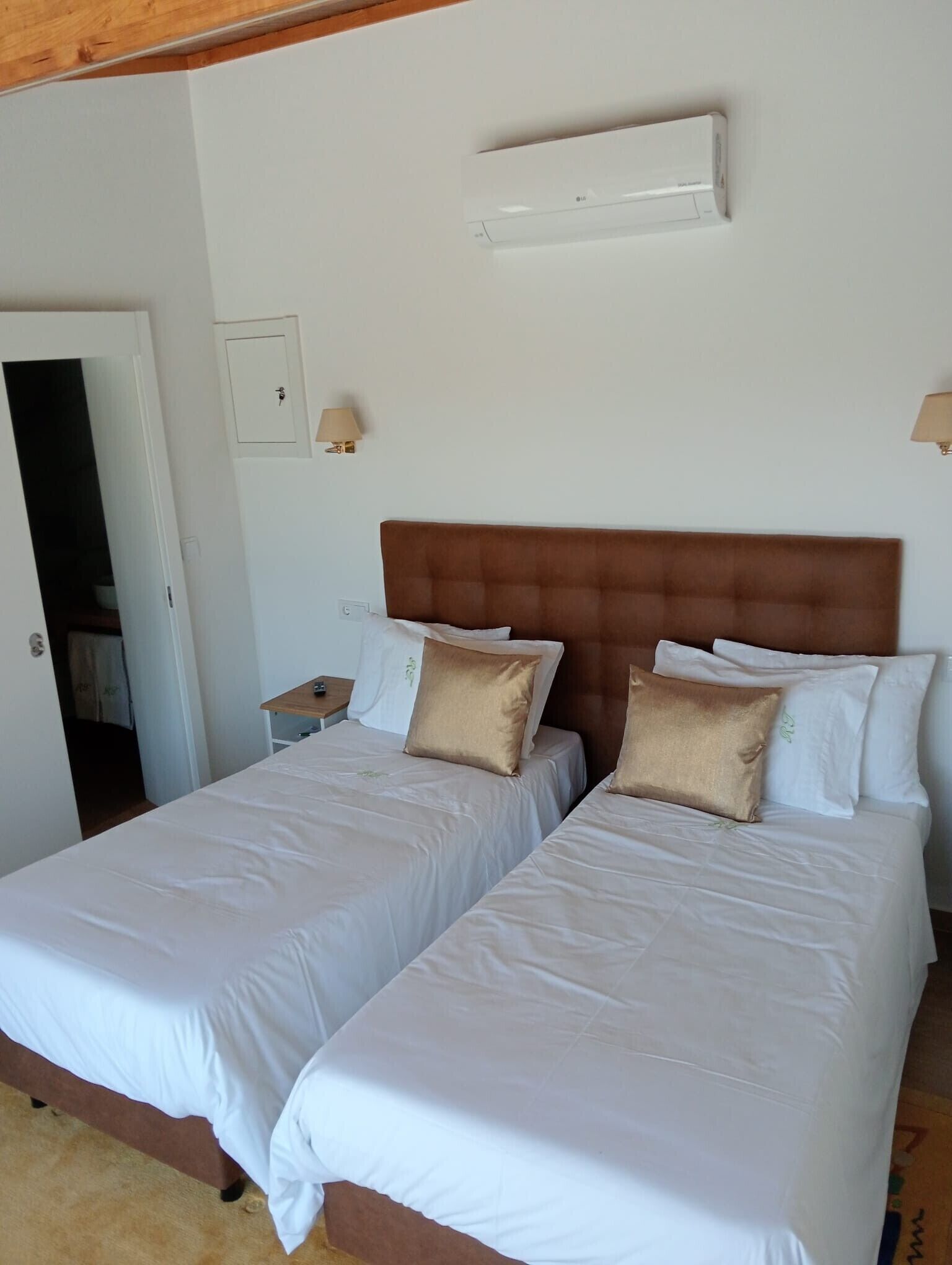 A double bed with a wooden headboard, white bedding, and two bedside lamps.