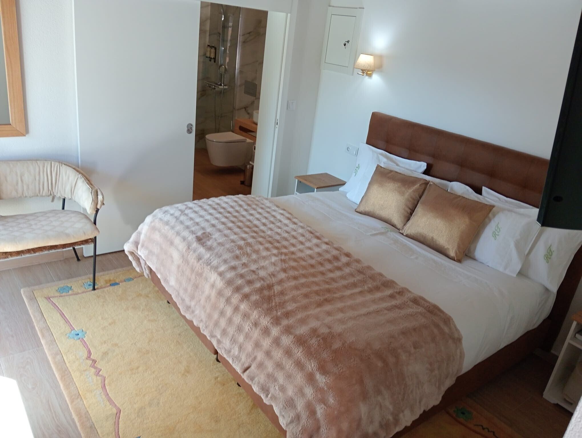 Ett sovrum med en säng, en stol, ett nattduksbord, en lampa och en duschhörna.