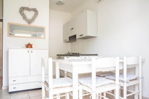 A white dining area with a table and chairs, a white cabinet, a heart-shaped decoration, and a mirror. - Bungalow im Marina di Cortellazzo Jesolo (Cortellazzo Jesolo)