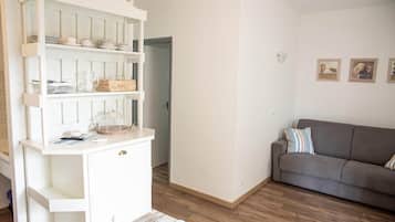 Une pièce avec une console blanche, un canapé gris et une porte donnant sur une autre pièce.