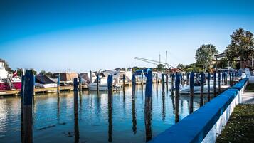 Un port de plaisance avec des bateaux amarrés, des poteaux en bois et un ciel bleu azur.