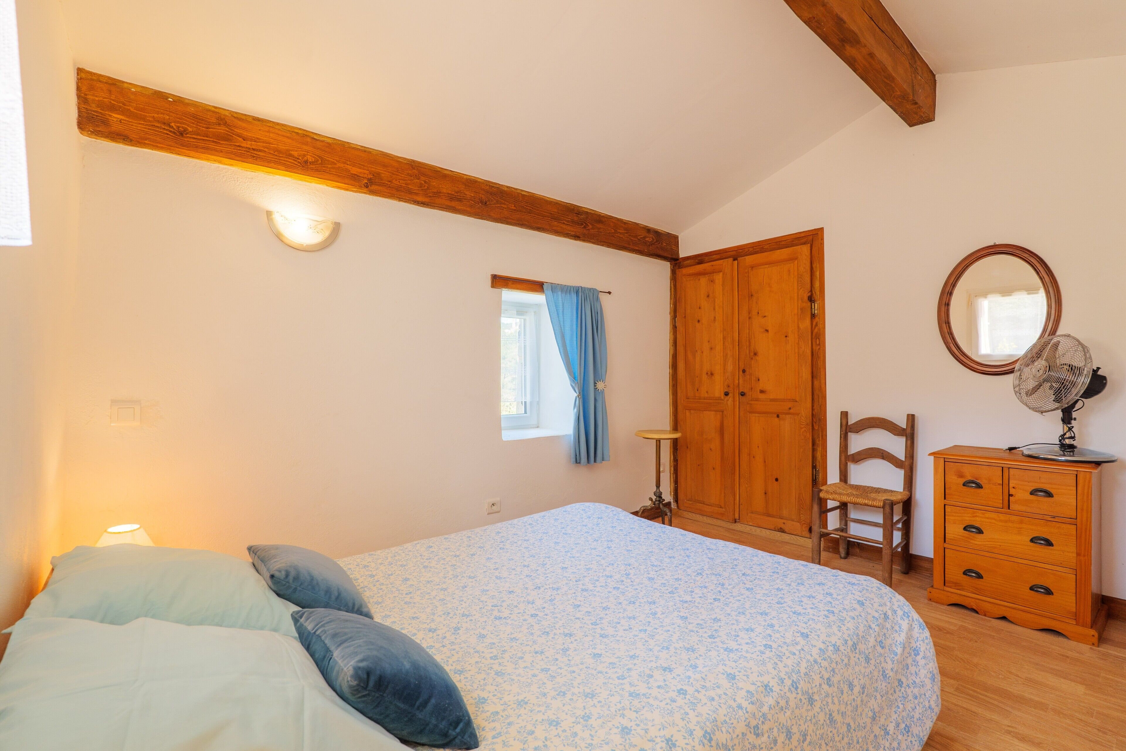 Un dormitorio con cama, cómoda de madera y espejo.