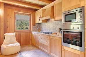 Eine Küche mit Holzausstattung, einer Mikrowelle, einem Backofen, einem Fenster mit Blick auf einen Wald und einem Sitzsack.
