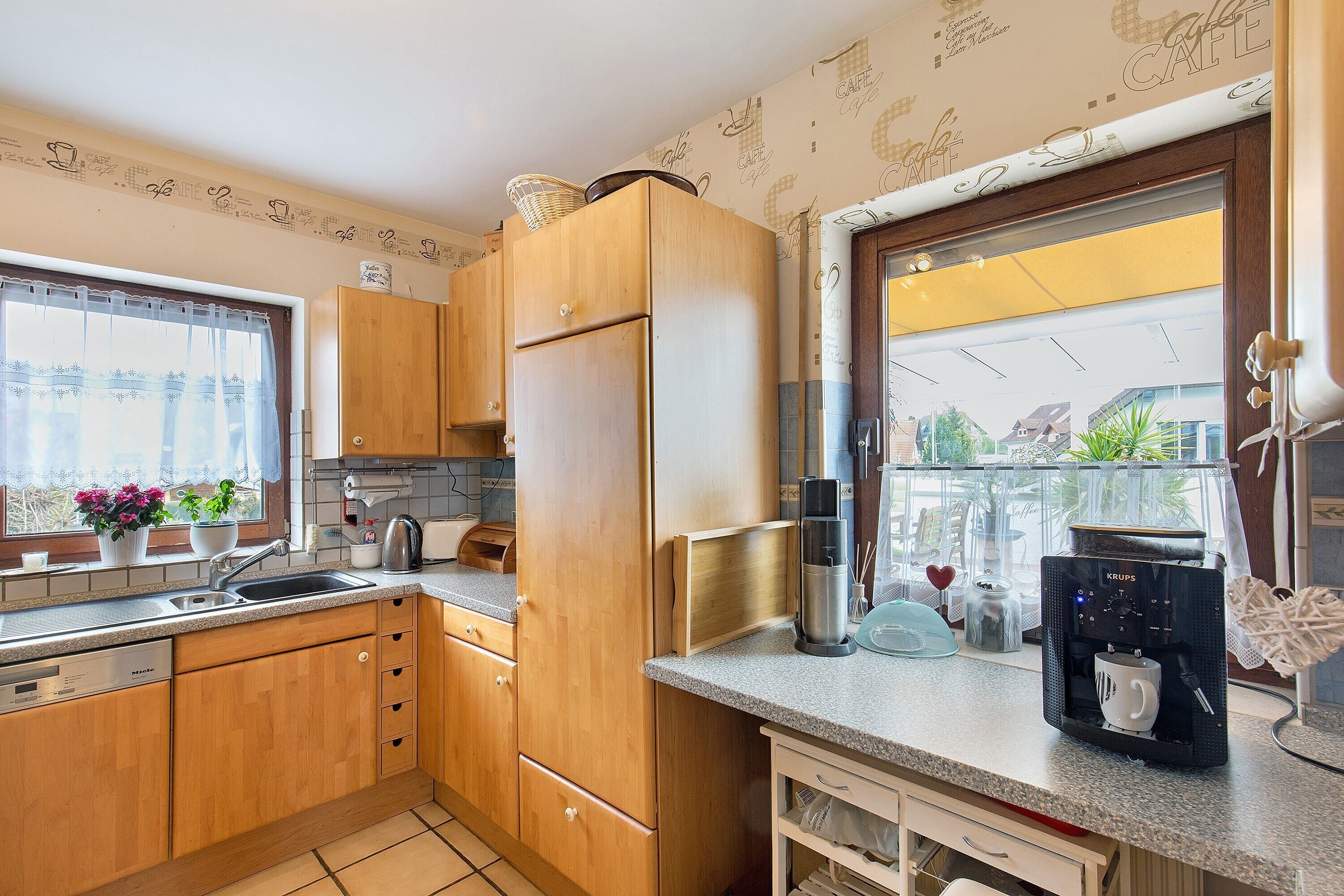 Una cocina con armarios de madera, un refrigerador de acero inoxidable, una cafetera y una ventana con vistas.