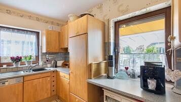 Una cocina con armarios de madera, un refrigerador de acero inoxidable, una cafetera y una ventana con vistas.