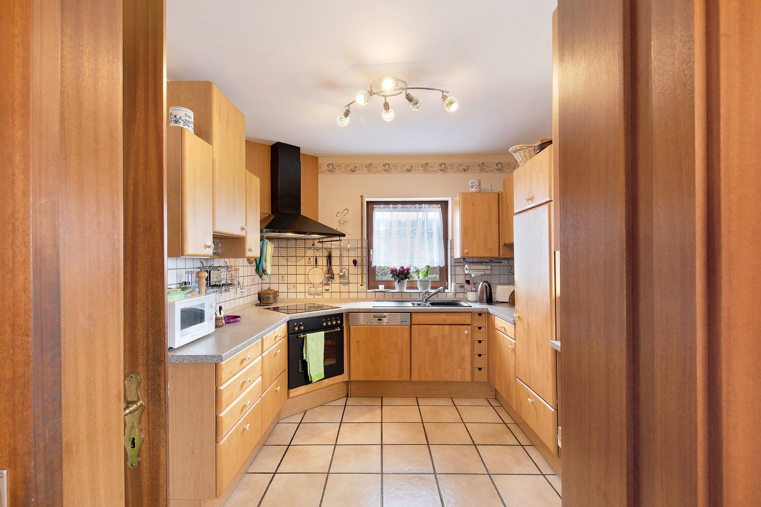 A kitchen with wooden cabinets, a microwave, a stove, and a sink.