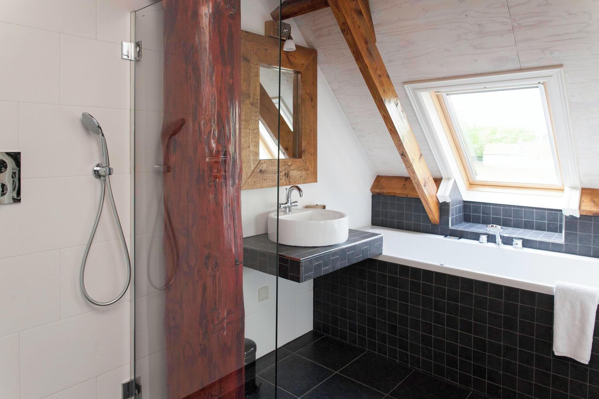 A modern bathroom with a glass shower enclosure, a white sink, and a large bathtub.