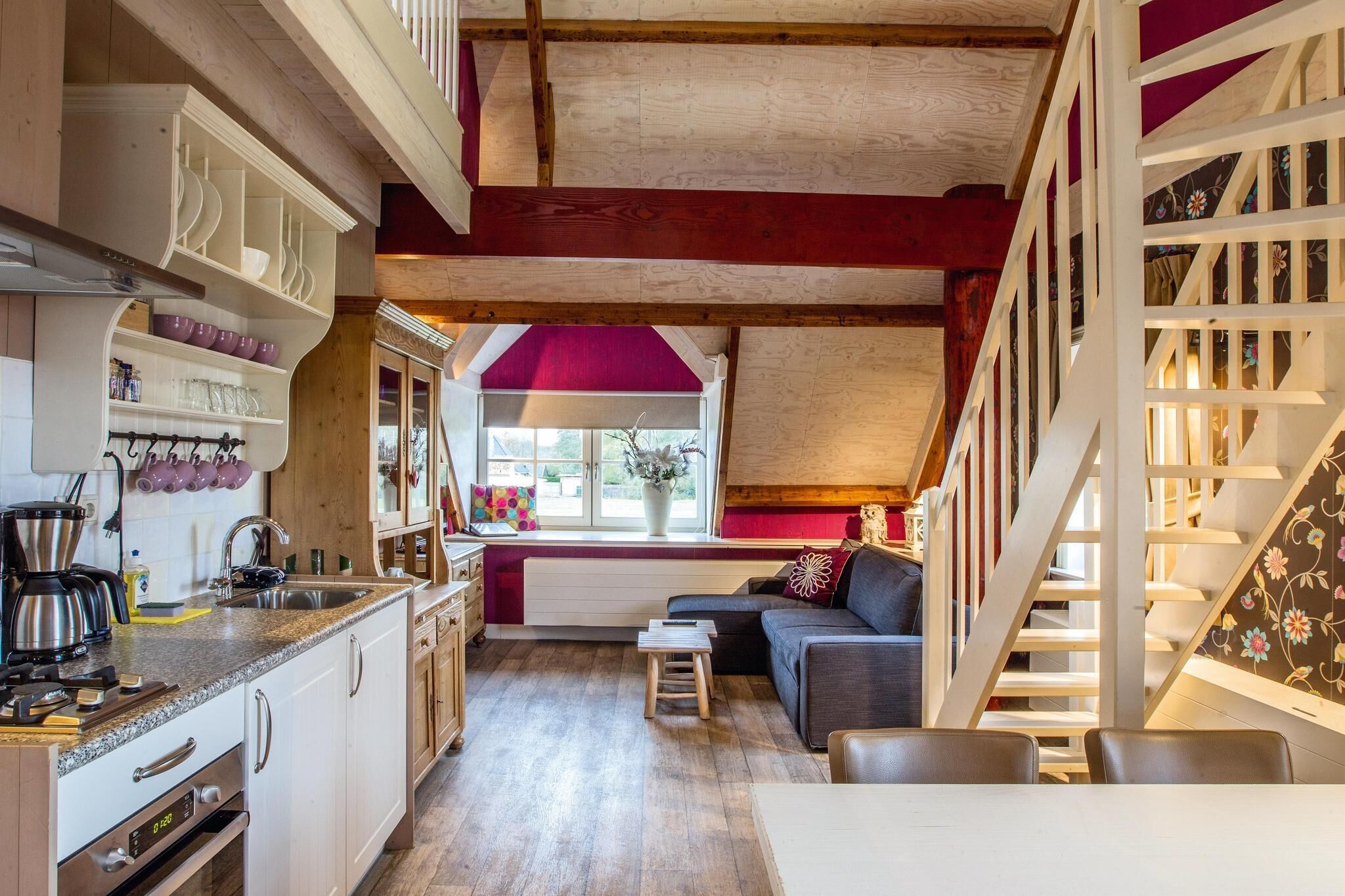 Eine kompakte Küche mit modernen Geräten, ein Essbereich mit kleinem Tisch und Stühlen sowie eine gemütliche Sitzecke mit Sofa und Kissen.