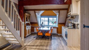 Een keuken met een houten tafel, oranje stoelen en een raam.