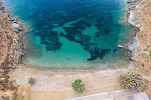 Eine Luftaufnahme einer Küstenlandschaft mit klarem, blauem Wasser, felsigen Ufern und spärlicher Vegetation.