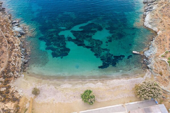 Vue aérienne d’une zone côtière caractérisée par des eaux d’un bleu limpide, des rivages rocheux et une végétation clairsemée.