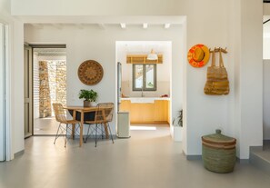 A modern kitchen with a stone wall, wooden cabinets, and a dining area with a table and chairs.