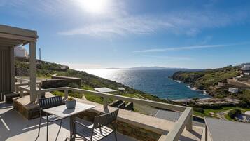 A terrace with a table and chairs overlooking a coastal landscape.