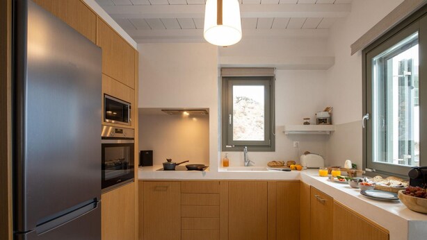 Una cocina moderna con armarios de madera, un refrigerador de acero inoxidable, un microondas y un ventanal que proporciona luz natural.