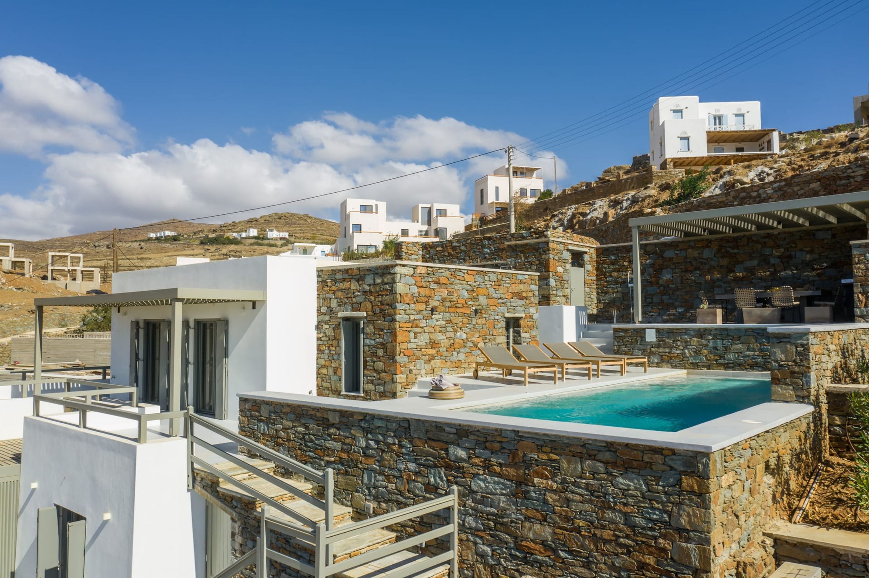 Ein modernes Gebäude mit Natursteinaußenfassade, einem Dachpool und Blick auf die umliegende Landschaft.