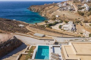 A coastal property with a swimming pool, terraced houses, and a view of the sea.