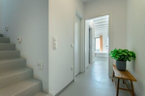 A staircase leading to a landing, a hallway with doors, and a wooden bench with a potted plant.