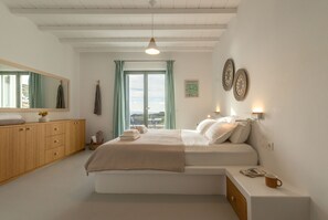 A bedroom with a bed, bedside table, and a view of the outdoors.