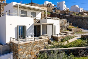A modern building with a stone facade, a balcony, and a staircase leading to an upper level. - Phos Villas Tinos (Tinos)