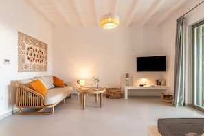 A modern living room with a sofa, a coffee table, a TV, and a decorative wall piece. - Phos Villas Tinos (Tinos)