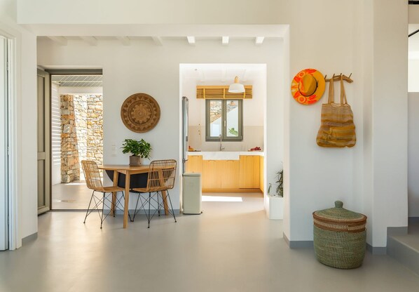 Une cuisine moderne avec un mur en pierre, des armoires en bois et un coin repas comprenant une table et des chaises.