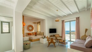 A modern living room with a sofa, a TV, and a balcony with a view.