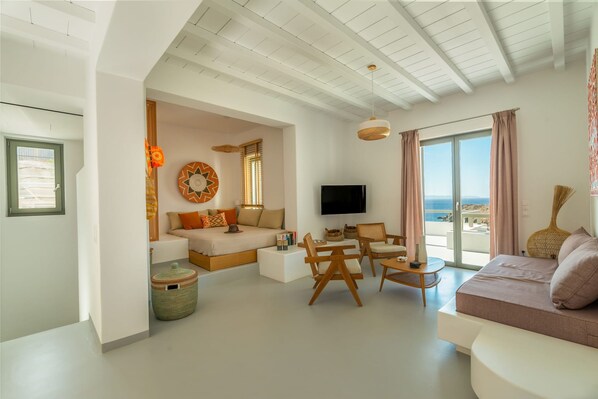 A modern living room with a sofa, a TV, and a balcony with a view.