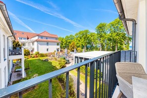 Ein Balkon mit Blick auf einen gepflegten Garten und angrenzende Häuser.