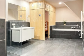 Ein modernes Badezimmer mit einer Duschkabine aus Holz, einem weißen Waschtisch und einer separaten Badewannenanlage.